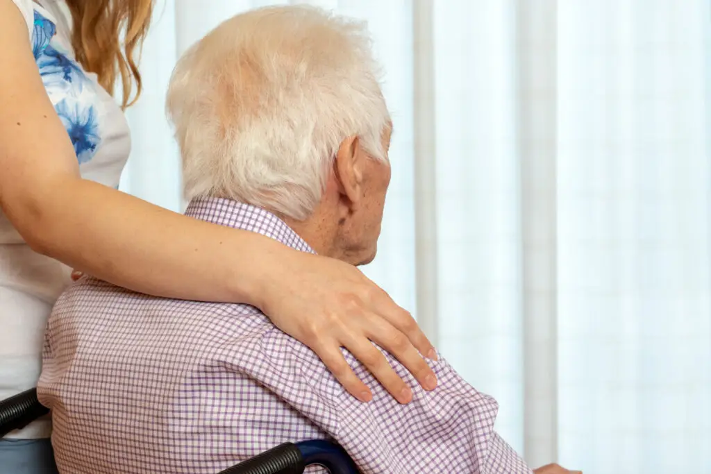 Rear view of old man with female hand on shoulder. - The Williamsport Home